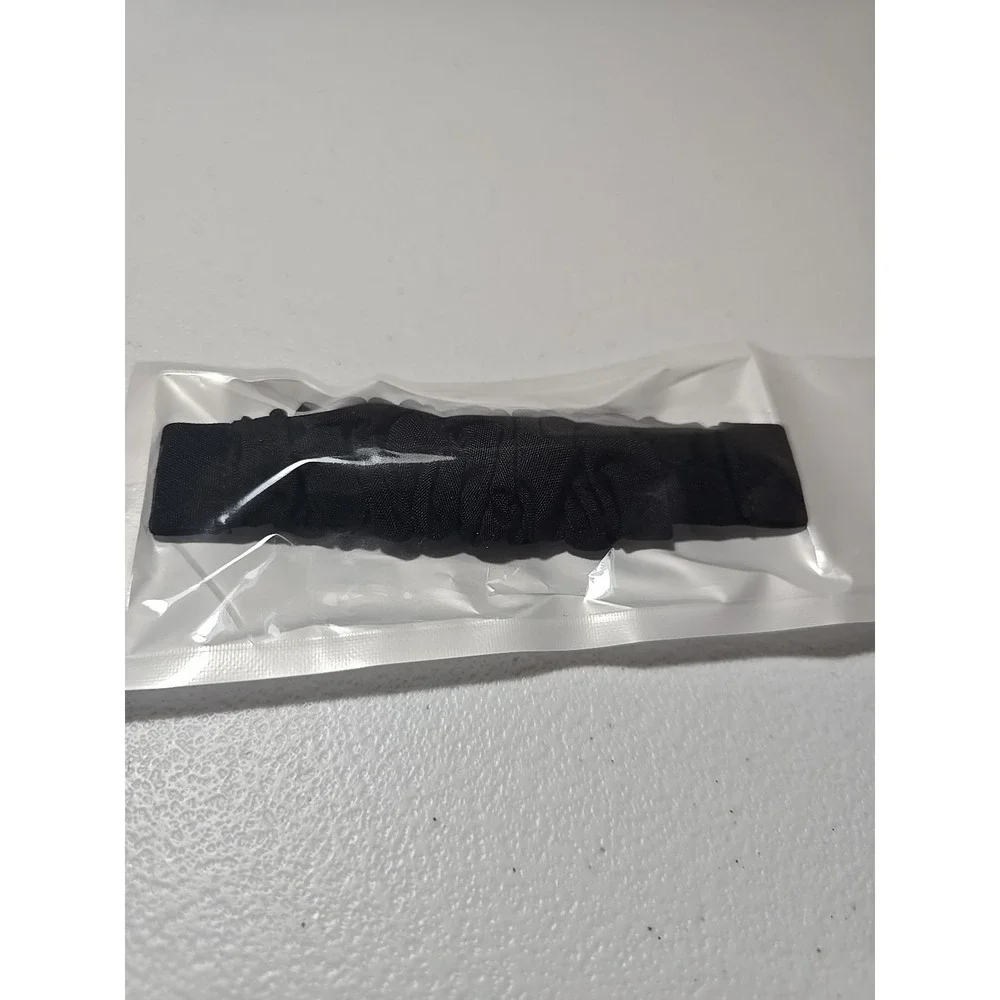 Scrunchie-style watch band for a fitness tracker, made of a black, ruched fabric
